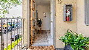 A hotel entrance with a wooden door, a small rug, a potted plant, and a fire extinguisher on the wall. - Downtown Mid-Century Modern Condo with Retro Vibes (Boise)