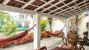 Une terrasse extérieure avec une table et des chaises en bois, un hamac et un sol en béton.