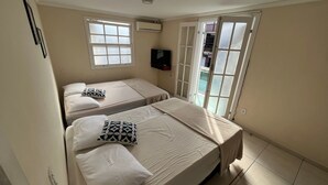 Une chambre avec deux lits, une télévision et une porte-fenêtre coulissante donnant sur un balcon.