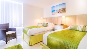 A hotel room with two beds, a chair, and a painting on the wall. - Spacious apartment, breathtaking sea views, private secure parking. (Newquay)