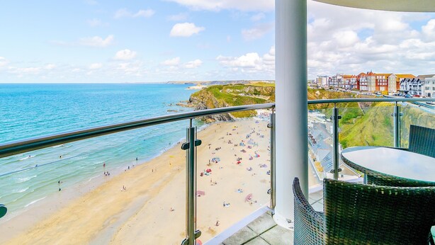 A balcony with a view of a beach and coastal buildings. - Spacious apartment, breathtaking sea views, private secure parking. (Newquay)