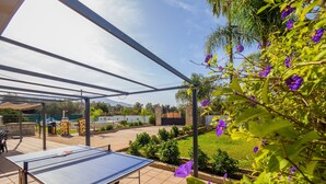 Ein Pingpongtisch unter einer Pergola mit Blick auf einen angelegten Garten und ein fernes Gebirge.