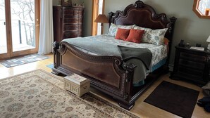 Een slaapkamer met een groot bed, een dressoir, een nachtkastje, een plafondventilator en uitzicht door een schuifdeur.