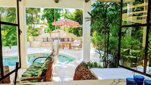 A poolside area with a lounge chair, a small table, and a hanging chair. - Designer's Villa At Playacar Beach (Playa del Carmen)