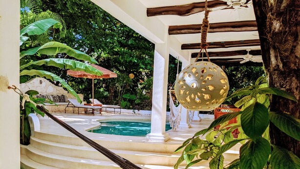 A pool area with a hammock, lounge chairs, and a hanging light fixture. - Designer's Villa At Playacar Beach (Playa del Carmen)