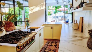 A kitchen with a gas stove, a sink, and a large window overlooking a garden. - Designer's Villa At Playacar Beach (Playa del Carmen)