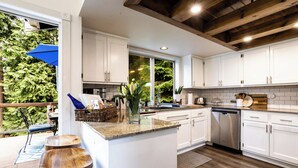 Een moderne keuken met witte kasten, een houten eiland en uitzicht op groen.