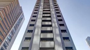 Un edificio alto y moderno con entrada de vidrio y plantas en macetas.