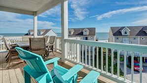 Una terraza techada con mobiliario exterior y vistas a casas de playa.