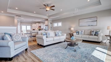 A spacious living room with a large sofa, a coffee table, and a dining area in the background.