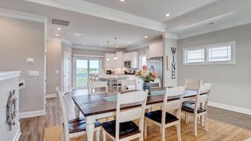 A spacious kitchen with white cabinets, a central island, and pendant lighting.