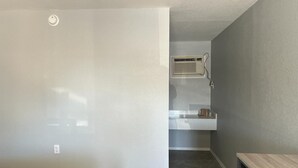 Una habitación con pared blanca, una ventana pequeña y una puerta.