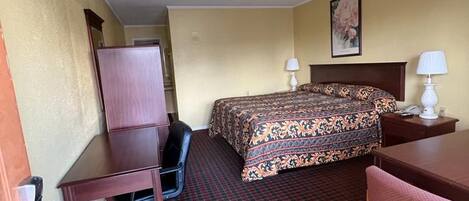 A hotel room with a bed, desk, chair, and a small table.