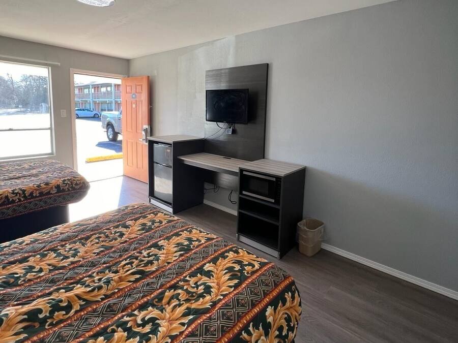 Una camera d'albergo con un letto, una scrivania, una televisione e vista sull'esterno.