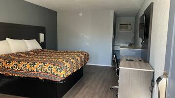 Una habitación de hotel con una cama grande, un escritorio, un espejo y un televisor.