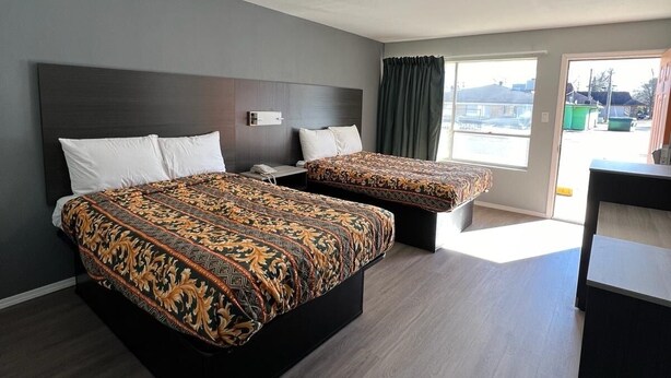 Habitación de hotel con dos camas, un escritorio y vistas al exterior.