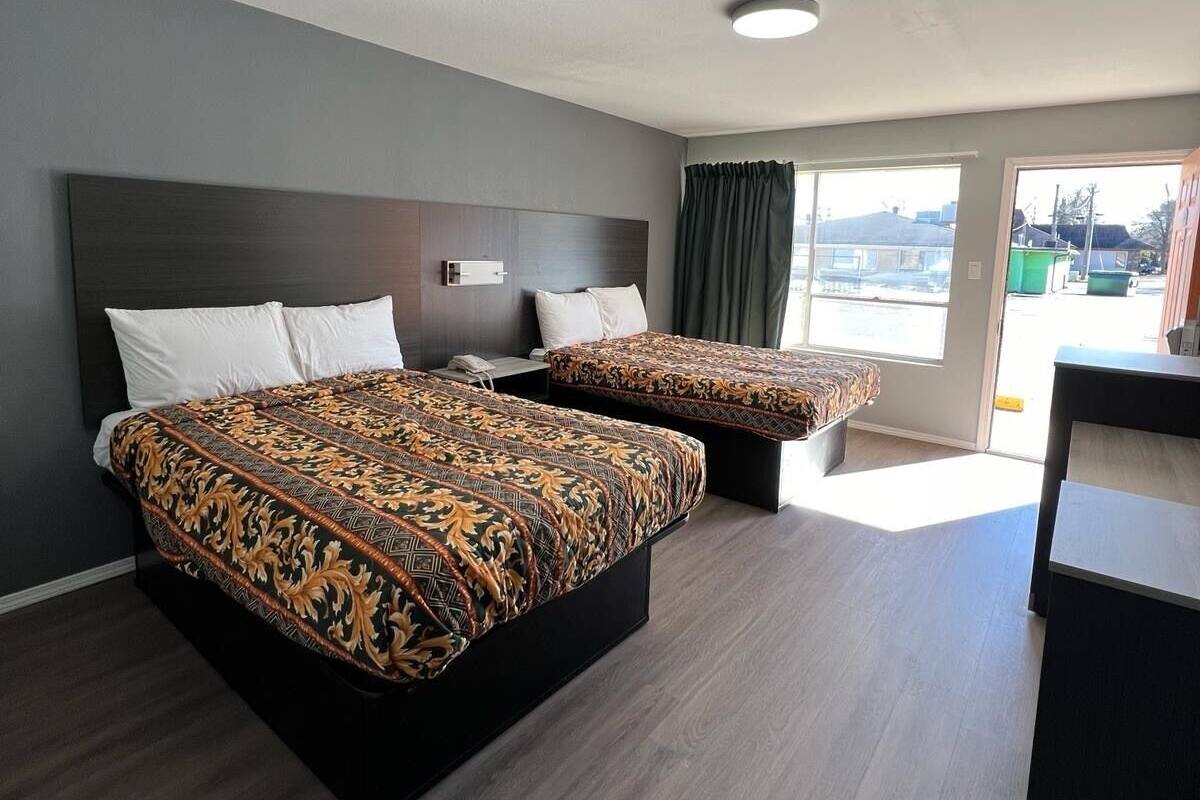 Une chambre d’hôtel avec deux lits, un bureau et une vue sur l’extérieur.