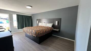 Una habitación de hotel moderna con una cama grande, un escritorio y un ventanal con cortinas.