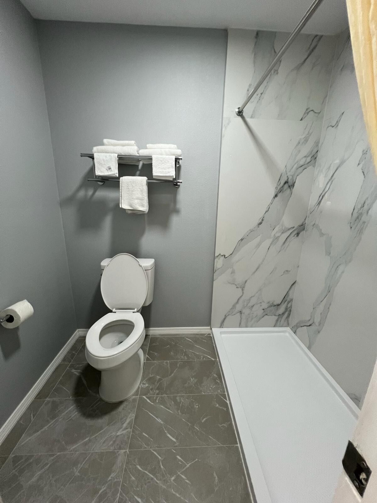 Un baño moderno con inodoro, toallero y zona de ducha.