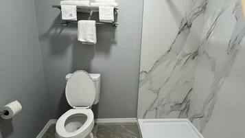 Un baño moderno con inodoro, toallero y zona de ducha.