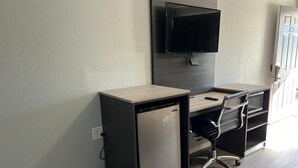 Un espacio de oficina compacto con escritorio, silla y un refrigerador pequeño.