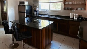 Een moderne keuken met een centraal eiland, een magnetron, een koelkast en een spoelbak.