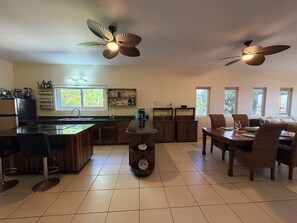 A spacious kitchen with a central island, dining area with chairs, and two ceiling fans. - Large 2-bedroom condo West End with stunning views and close to beach (West End)