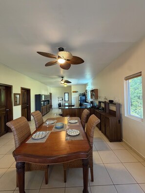 A spacious dining area with a large wooden table, multiple chairs, and ceiling fans. - Large 2-bedroom condo West End with stunning views and close to beach (West End)