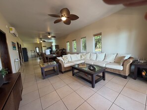 A spacious living area with a sofa, coffee table, and ceiling fans. - Large 2-bedroom condo West End with stunning views and close to beach (West End)
