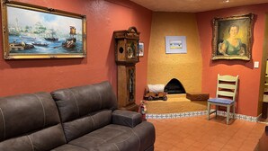 Ein Wohnzimmer mit braunem Ledersofa, Kamin, Holzschrank und zwei gerahmten Bildern an den Wänden.