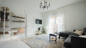 A modern living room with a sofa, a coffee table, a TV, and a chandelier.
