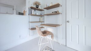 A white room with a white chair, wooden shelves, and a white door.