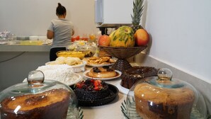 A buffet table with various dishes, including fruits, pastries, and desserts. - Honório Pousada  (Tucano)