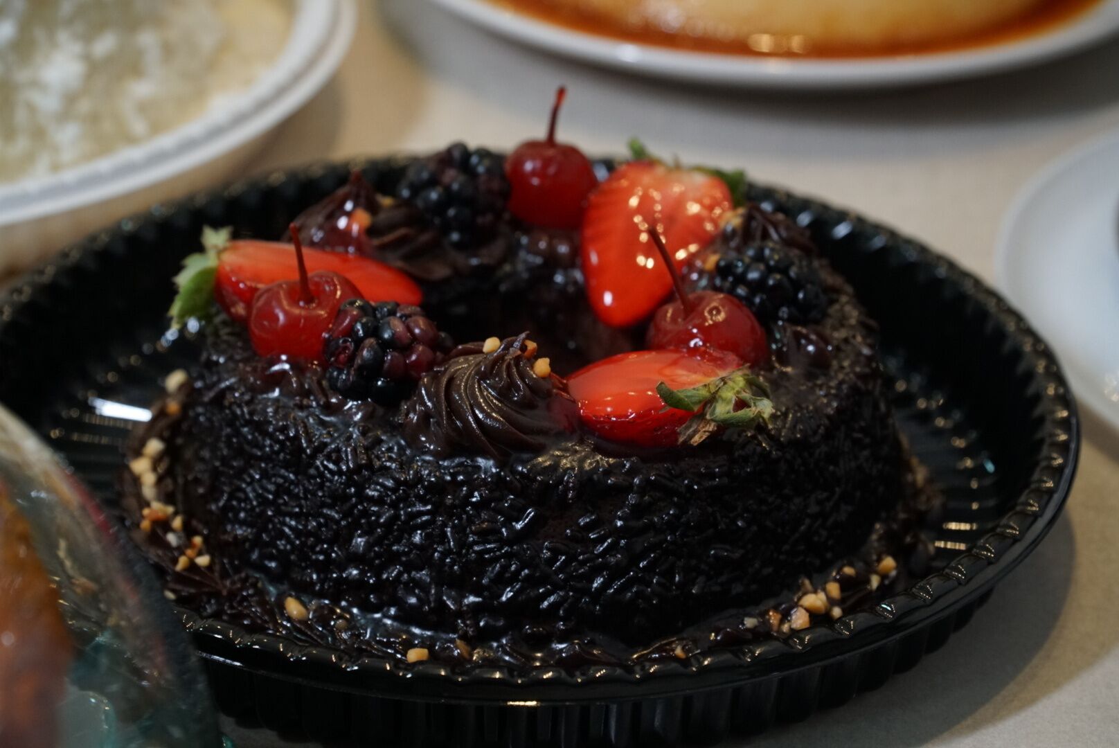 A dessert with cherries and chocolate on a black plate.