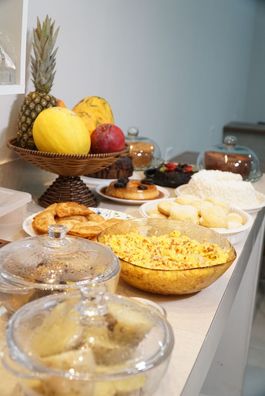 Un bufé con diversas opciones de comida, incluyendo frutas, pasteles y un tazón grande de huevos revueltos.