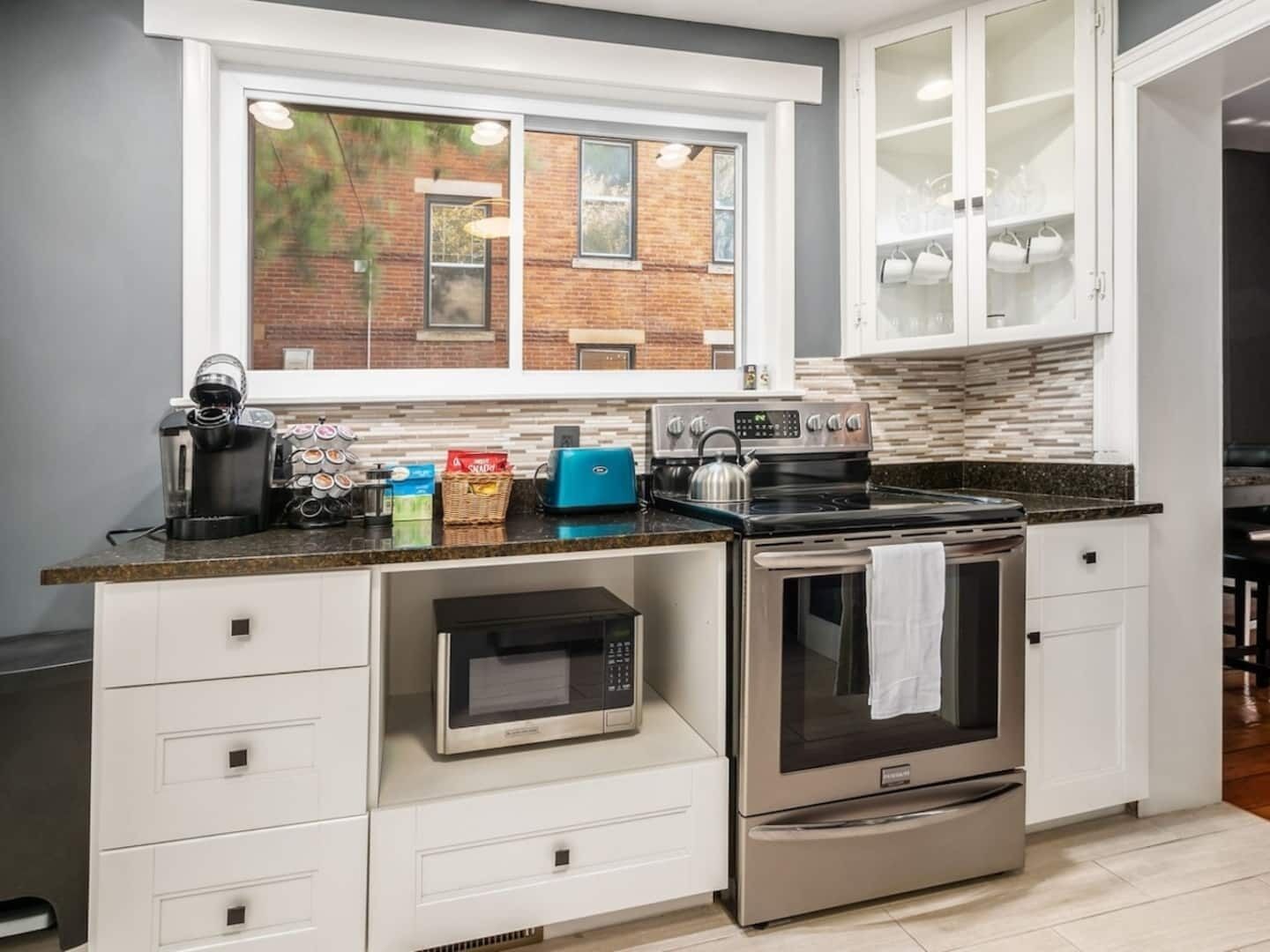 Een moderne keuken met een ingebouwde magnetron, kookplaat en koffiezetapparaat.
