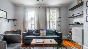 Ein modernes Wohnzimmer mit einer grauen Couch, einem Couchtisch und einem Bücherregal.