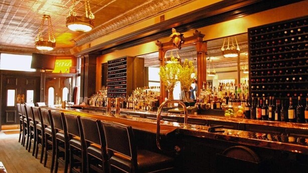 Eine Bar mit einer langen Theke, mehreren Weinständen und einer Reihe von Ledersesseln.