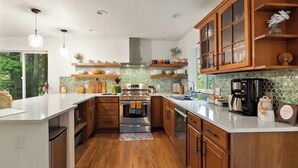 Une cuisine moderne avec des meubles en bois, un four en acier inoxydable et un grand îlot central.