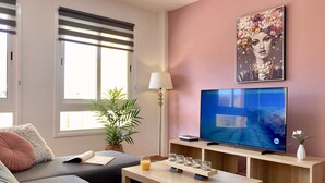 Ein modernes Wohnzimmer mit einer Couch, einem Couchtisch, einem Fernseher und einem Blumentopf.