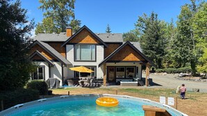 A two-story house with a backyard swimming pool, a hot tub, and a covered patio area. - Seabrook Farmhouse with Hot Tub & Swimming Pool, 4 min to Butchart Gardens  (Saanichton)