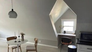 A dining area with a round table and chairs, a trash bin, and a kitchen area with cabinets and a microwave. - Modern Large Studio Apartment in Heart of Tremont. (Cleveland)
