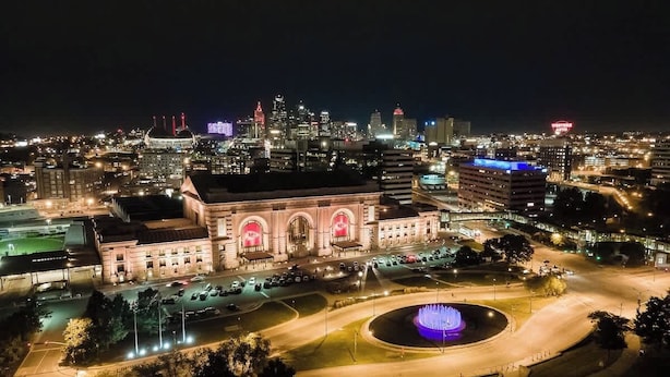 A cityscape at night with a prominent building featuring arched windows and a fountain in the foreground. - Cozy KC Suburb Home, Sleeps8_ PoolTable_ Foosbal (Mission)