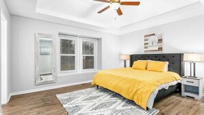 A bedroom with a bed, two bedside tables, a ceiling fan, and a window with blinds. - Home Near Legends_Sleeps 8_Great Location_Shops (Kansas City)