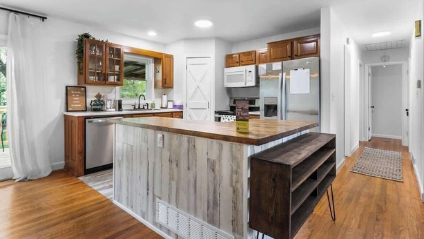A modern kitchen with wooden cabinets, a central island, and built-in appliances. - Kid-Friendly Home w/ Yard & Workspace (Shawnee)