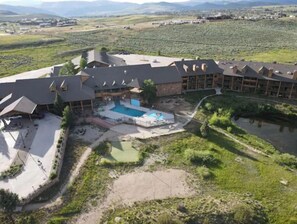 A resort with a swimming pool, multiple buildings, and a landscaped area with a pond.