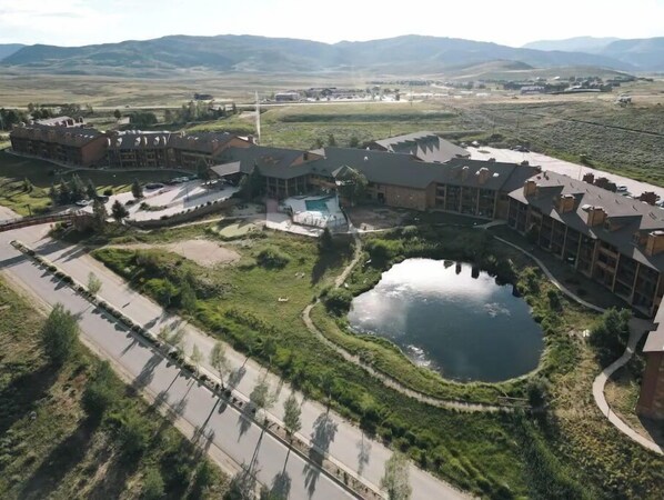 A hotel with multiple buildings, a swimming pool, and a large pond.