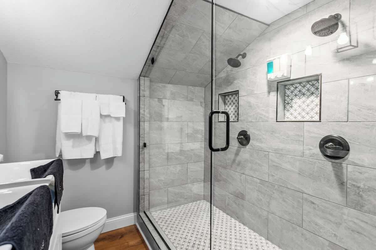 Une salle de bain moderne dotée d’une douche à parois de verre, de toilettes et d’une baignoire.