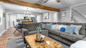 Ein modernes Wohnzimmer mit grauem Sofa, Holztisch und Deckenventilator.
