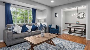 A living room with a grey sofa, blue and white cushions, a wooden coffee table, and a patterned rug. - Family Fave w/2 Living Spaces_4BR_Great Location (Overland Park)